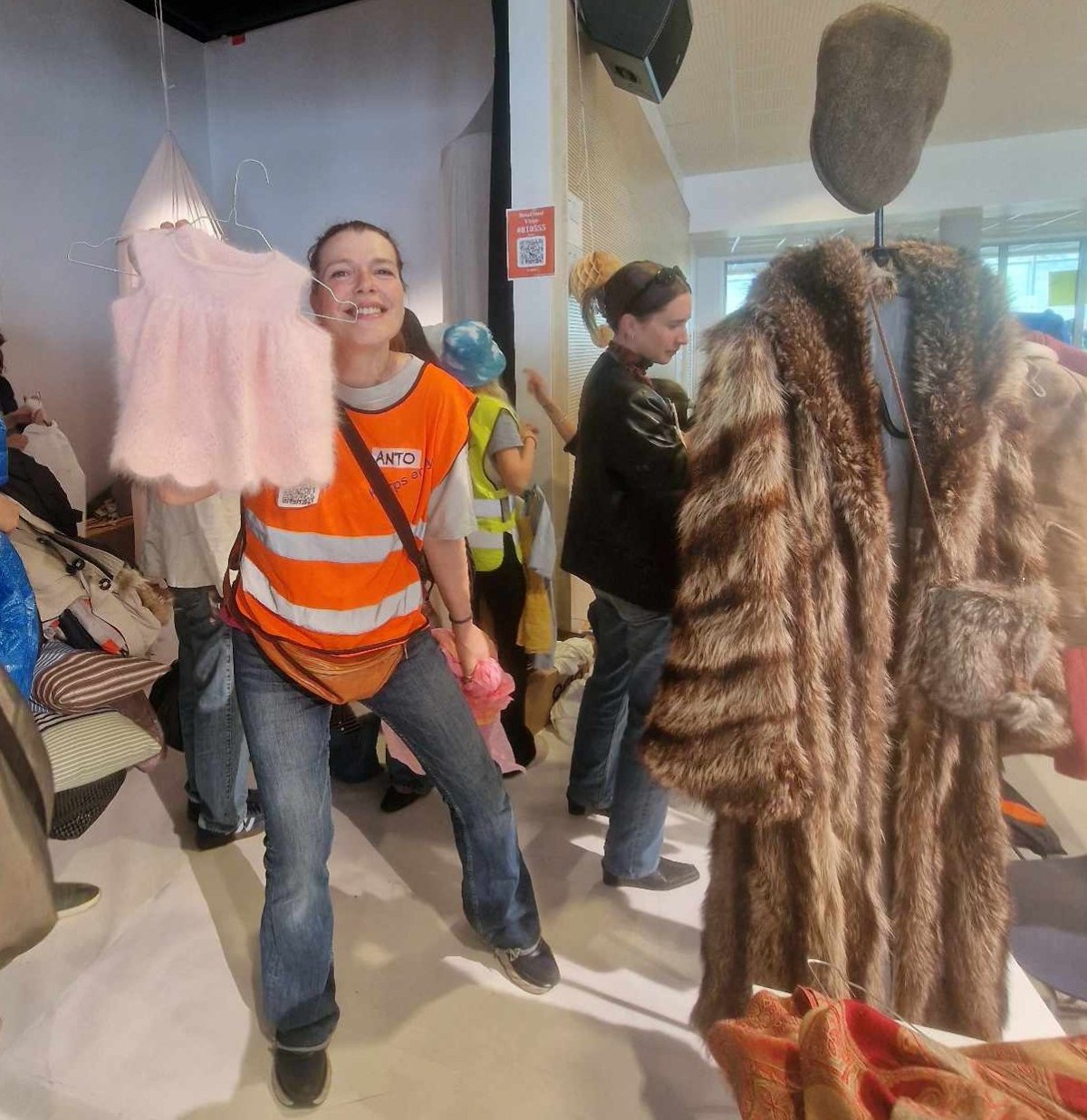 Ansatt på loppemarkedet viser klær på loppemarkedet på Kjelsås.